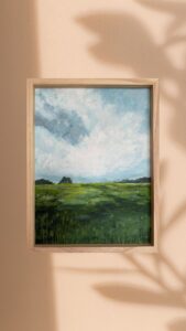 Obraz przedstawiający szeroki horyzont, błękitne niebo i soczystą, gęstą trawę – pejzaż pełen spokoj