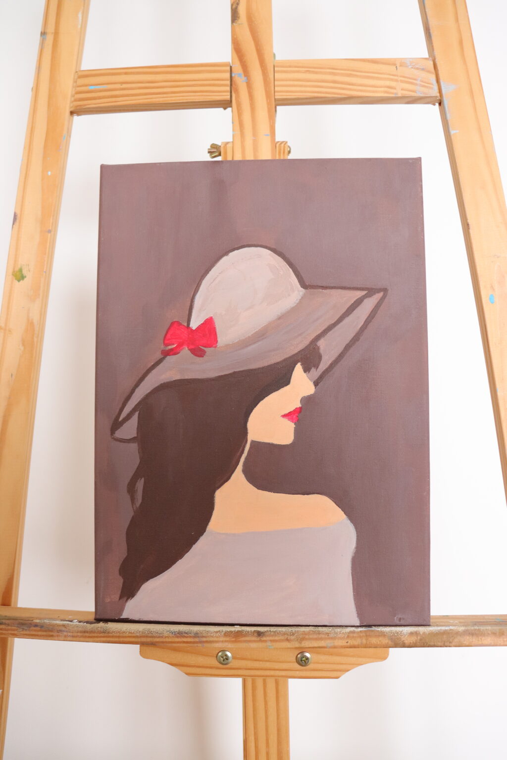 Kobieca sylwetka uchwycona w półprofilu. Kontrast ciemnych włosów  z akcentem czerwieni nadaje kompozycji wyrazistości i elegancji.