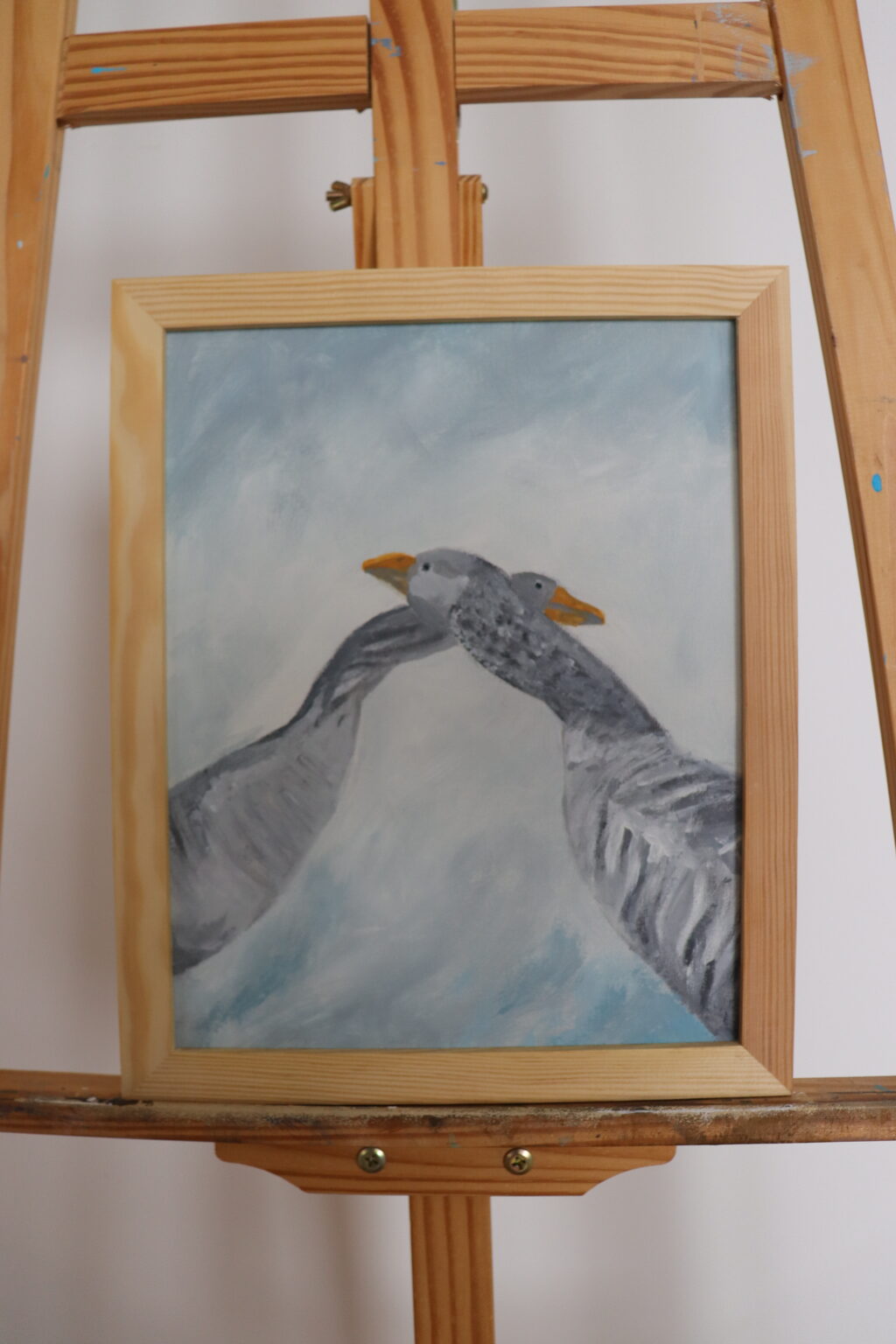 Obraz przedstawia dwie gęsi, których szyje splatają się w delikatnym geście bliskości.